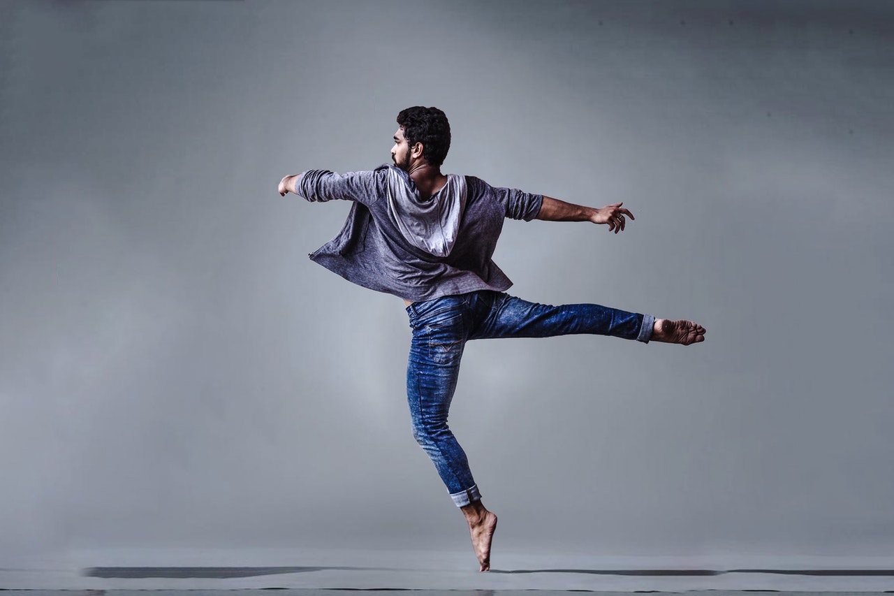 Man wearing blue jeans doing a pirouette spin in dance studio